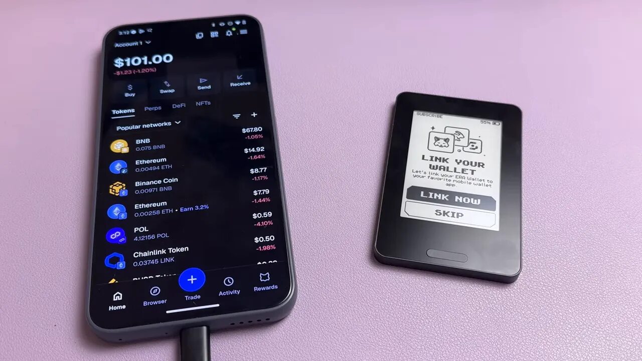 Smartphone showing a mobile wallet app dashboard next to an Era hardware wallet on a pink surface