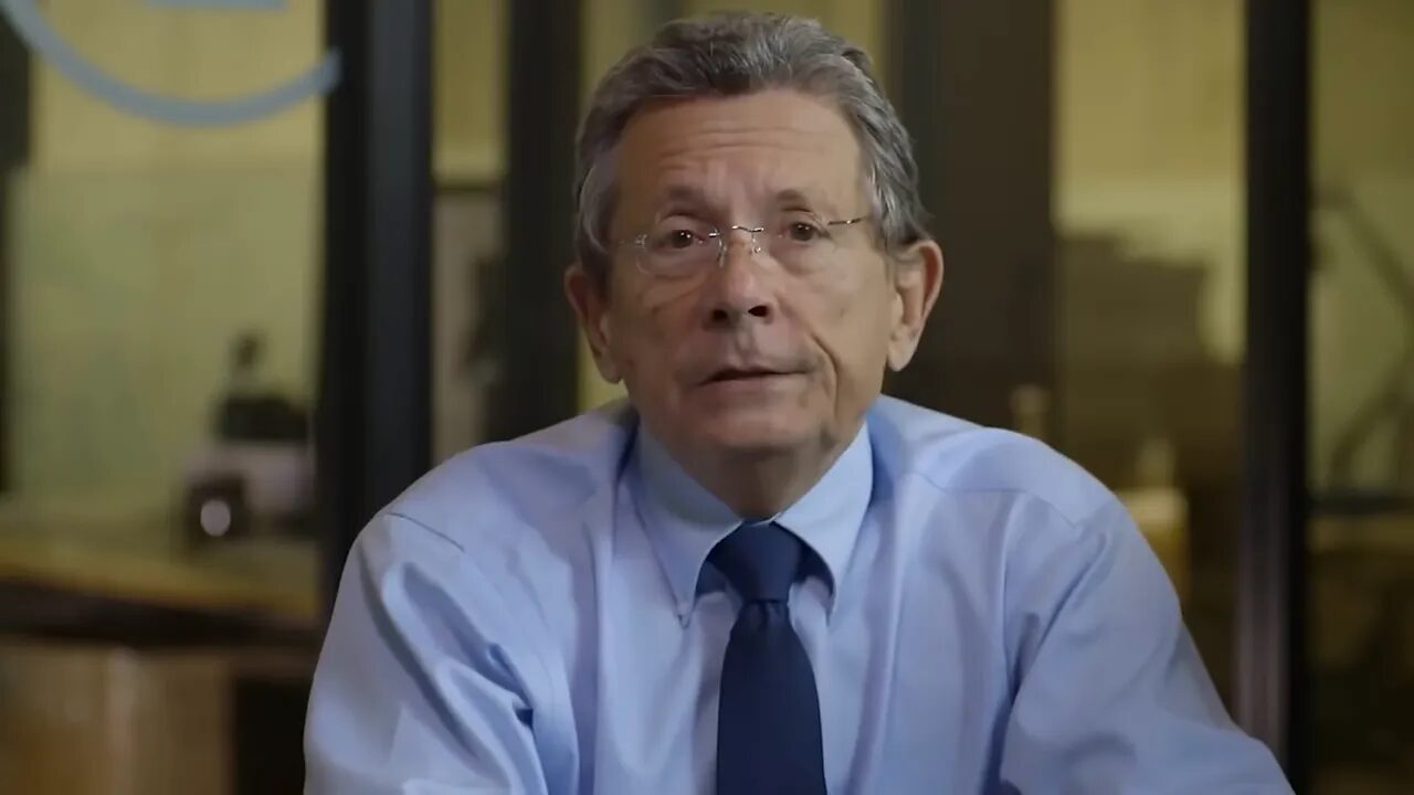 centered speaker in blue shirt and tie explaining trading concepts to camera