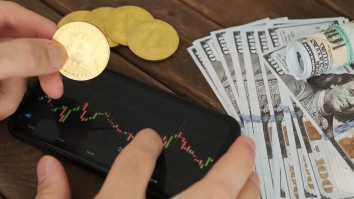bitcoin coins, US dollar bills and a smartphone showing a candlestick price chart