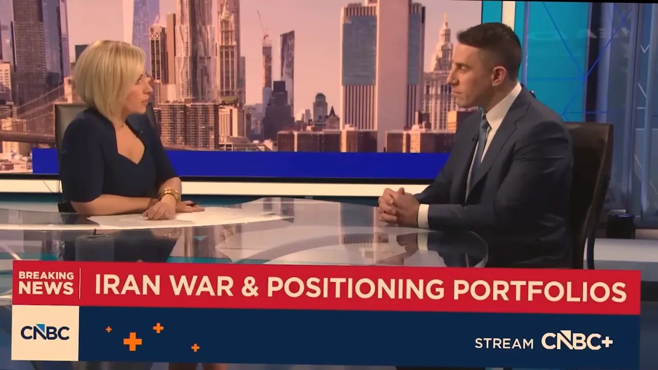 TV studio interview with on-screen headline 'IRAN WAR & POSITIONING PORTFOLIOS' on a CNBC broadcast.