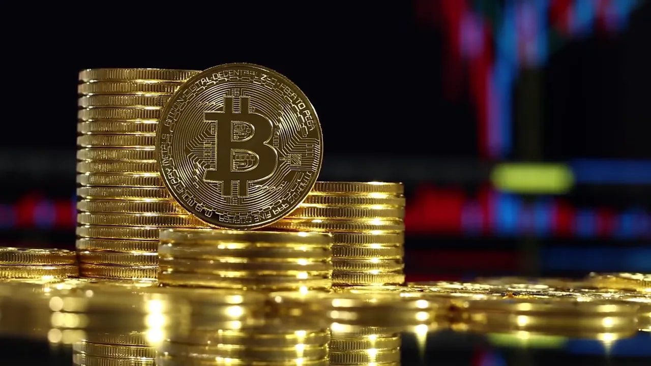 Golden Bitcoin coin in front of stacked gold bars